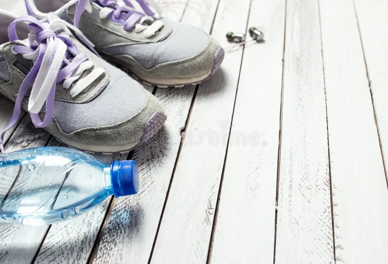 Balanced lifestyle scene showing walking shoes, water bottle, and planner on a wooden surface